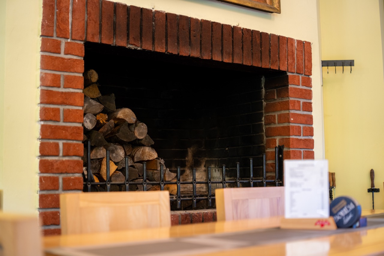 Zděný krb s připraveným dřevem v restauraci