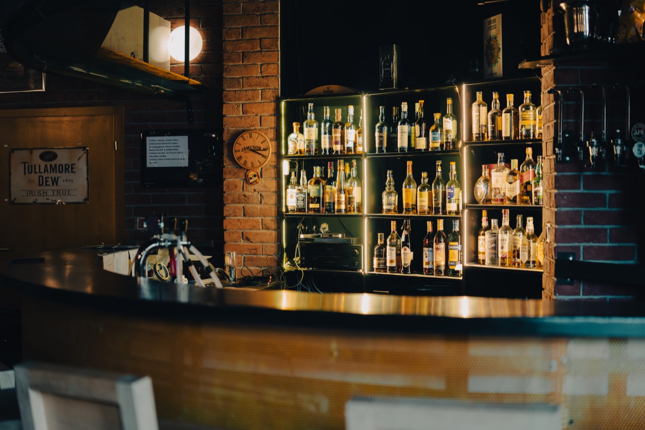 Whisky bar: nasvícené police se skotskými a irskými whisky za barem